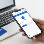 Osoba doładowująca telefon przez internet za pomocą laptopa i karty płatniczej